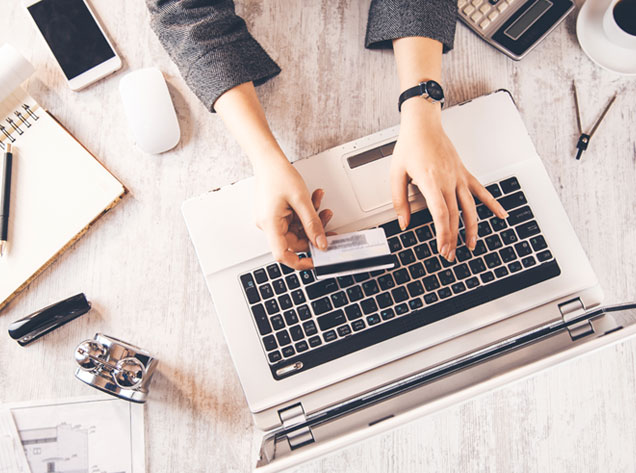 hands holding credit card over laptop